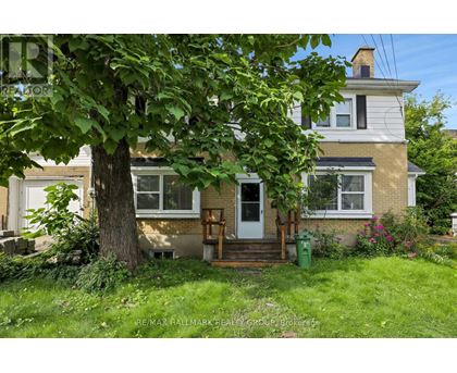 A tree in front of a house with a white door.