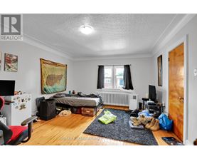 A bedroom with a bed, a chair, and a dungeons and dragons poster on the wall.