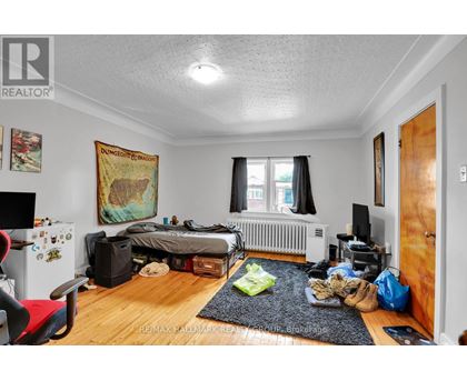 A bedroom with a bed, a chair, and a dungeons and dragons poster on the wall.