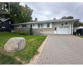 A house with a driveway and a large rock in the front yard.