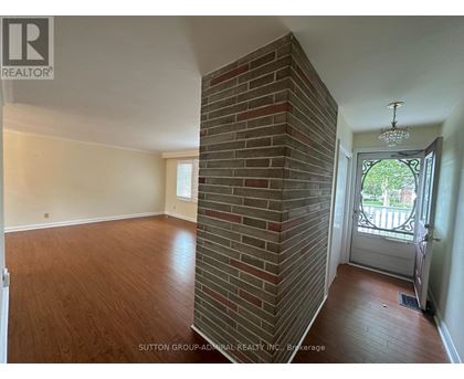 A room with a brick pillar and a door leading outside.