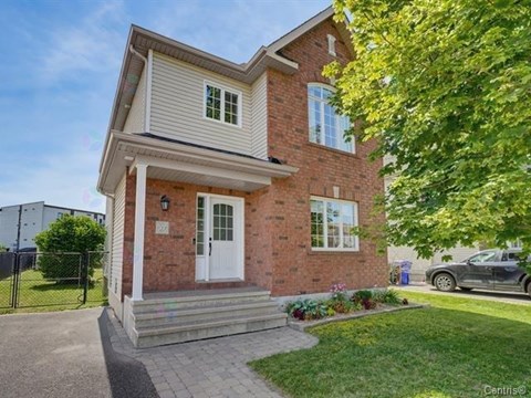 A house with a white door and windows is surrounded by greenery.
