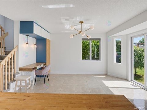 A spacious room with a wooden floor and a chandelier hanging from the ceiling.