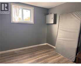 A room with a grey wall and a window with white curtains.