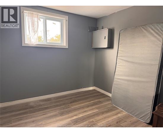 A room with a grey wall and a window with white curtains.