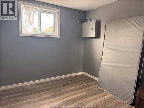 A room with a grey wall and a window with white curtains.