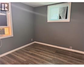 A room with a grey wall and a wooden floor.