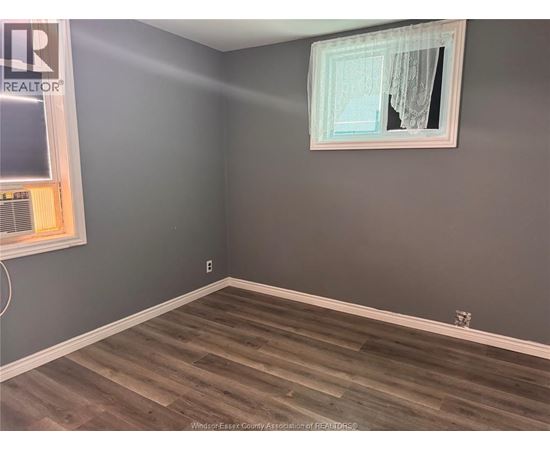 A room with a grey wall and a wooden floor.