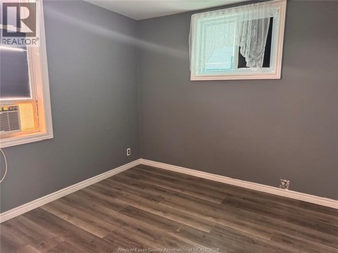 A room with a grey wall and a wooden floor.