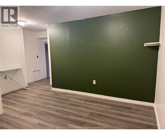 A room with a green wall and wooden flooring.