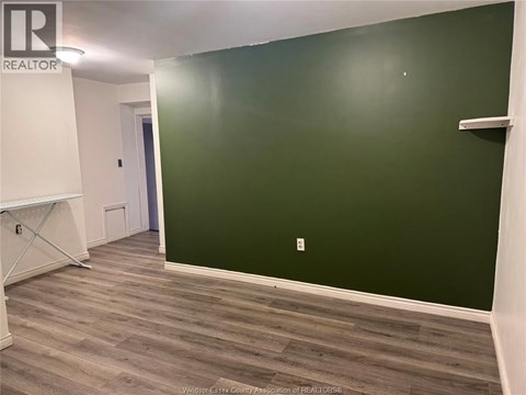 A room with a green wall and wooden flooring.