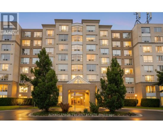 A large, well-lit apartment building with a central entrance and trees in front.