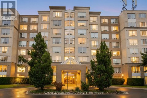 A large, well-lit apartment building with a central entrance and trees in front.