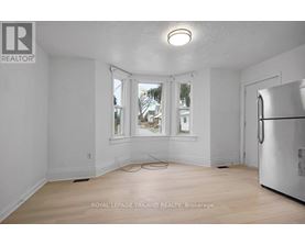 A white room with a window and a refrigerator.