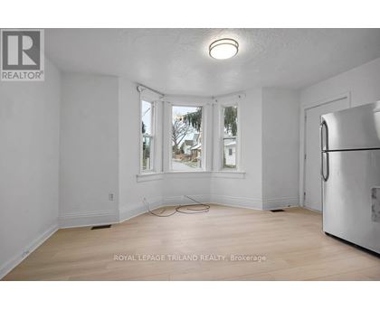 A white room with a window and a refrigerator.