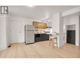 A kitchen with a refrigerator, stove, and bar stool.