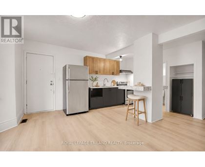 A kitchen with a refrigerator, stove, and bar stool.