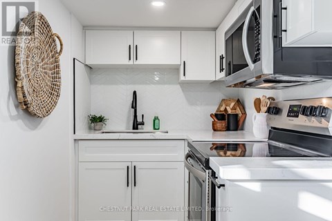 A modern kitchen with white cabinets and stainless steel appliances.