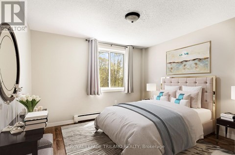 A well-lit bedroom with a large bed and a painting on the wall.