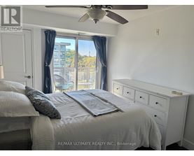 A bedroom with a bed, dresser, and window with a view of a building outside.