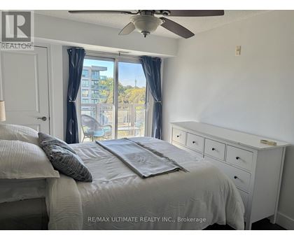 A bedroom with a bed, dresser, and window with a view of a building outside.