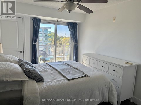 A bedroom with a bed, dresser, and window with a view of a building outside.