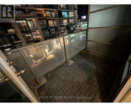 A balcony of a building with a glass railing and tiled floor.