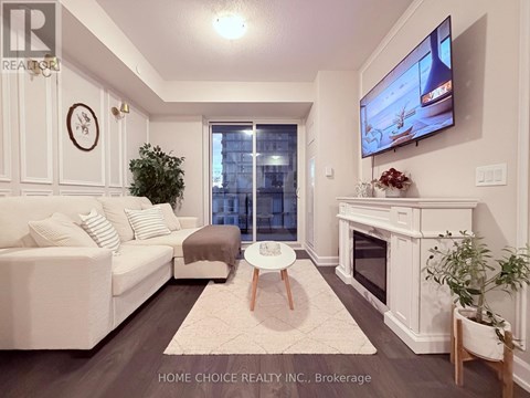 A living room with a white couch, a flat screen TV, and a fireplace.