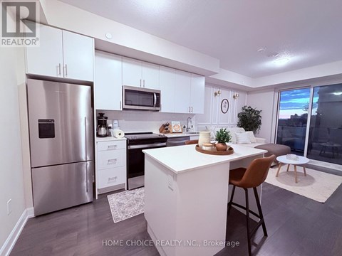 A modern kitchen with white cabinets and a stainless steel refrigerator.