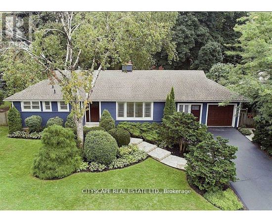 A blue house with a white trim is surrounded by greenery.