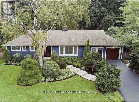 A blue house with a white trim is surrounded by greenery.