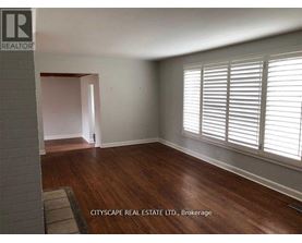 A room with wooden floors and white walls, with a window on the right side.