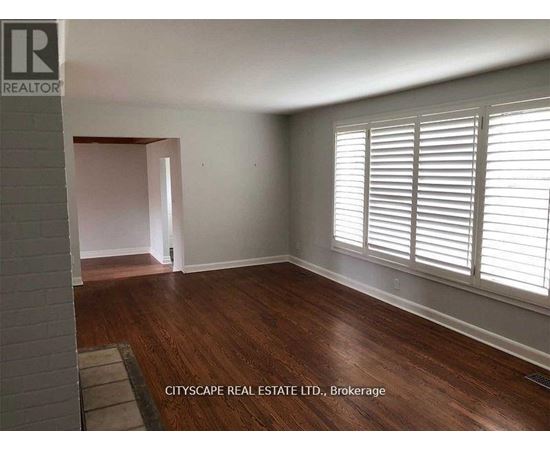 A room with wooden floors and white walls, with a window on the right side.