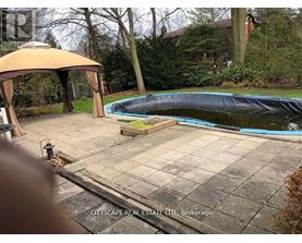 A pool covered with a black tarp sits in a backyard.
