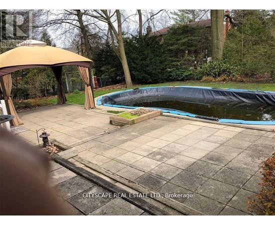 A pool covered with a black tarp sits in a backyard.