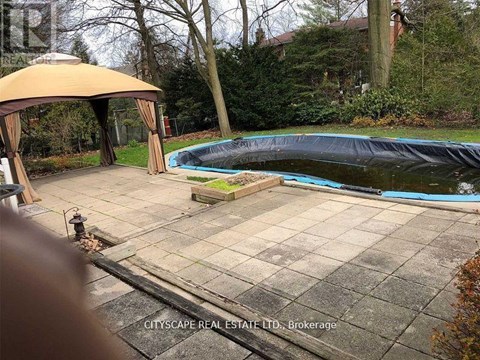 A pool covered with a black tarp sits in a backyard.