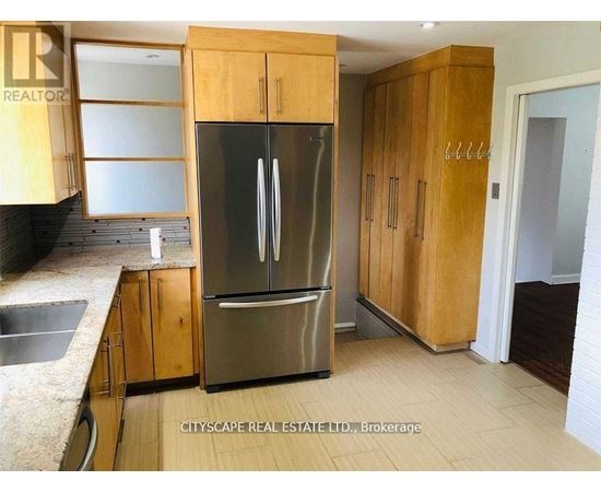 A kitchen with wooden cabinets and a stainless steel refrigerator.