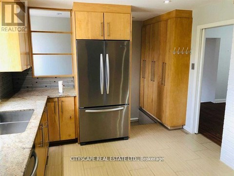 A kitchen with wooden cabinets and a stainless steel refrigerator.