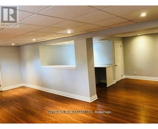 A room with wooden floors and white walls, with a window and a door visible.