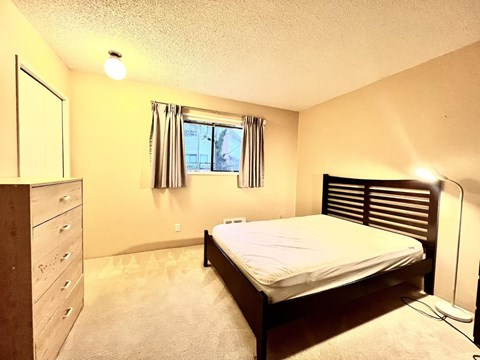 A bedroom with a bed, dresser, and window.