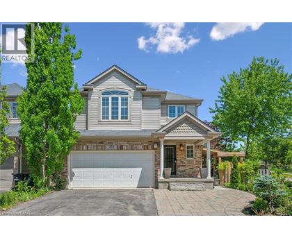 A house with a grey roof and a white garage door is surrounded by greenery.