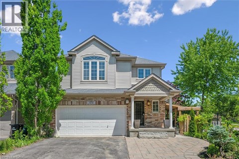 A house with a grey roof and a white garage door is surrounded by greenery.