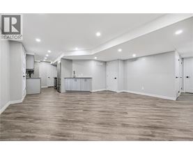A spacious room with wooden flooring and white walls.
