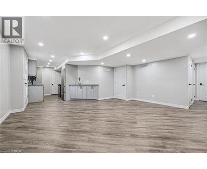 A spacious room with wooden flooring and white walls.