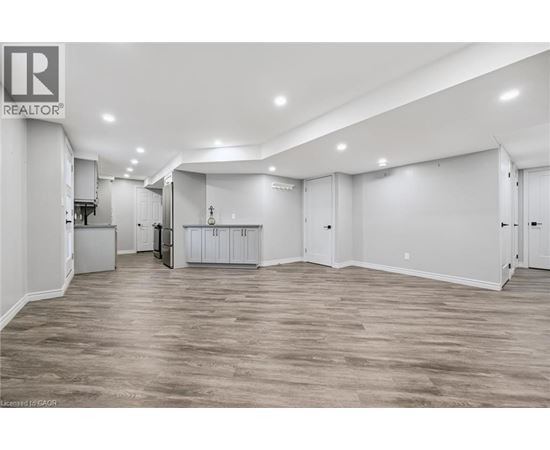 A spacious room with wooden flooring and white walls.