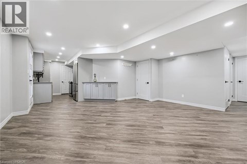 A spacious room with wooden flooring and white walls.