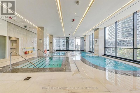 A large indoor swimming pool with a glass wall on one side.