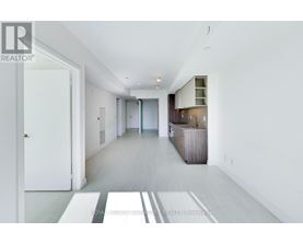 A spacious, white-walled hallway with a wooden floor and a white door on the left.