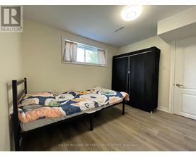 A bedroom with a bed, a window with curtains, and a black wardrobe.