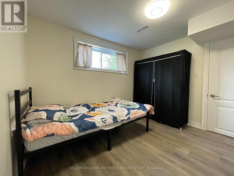 A bedroom with a bed, a window with curtains, and a black wardrobe.